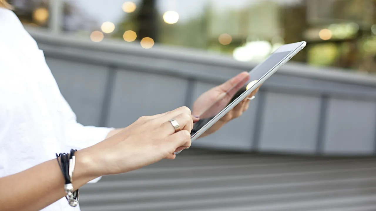 Person adjusting settings on a tablet beside a television remote